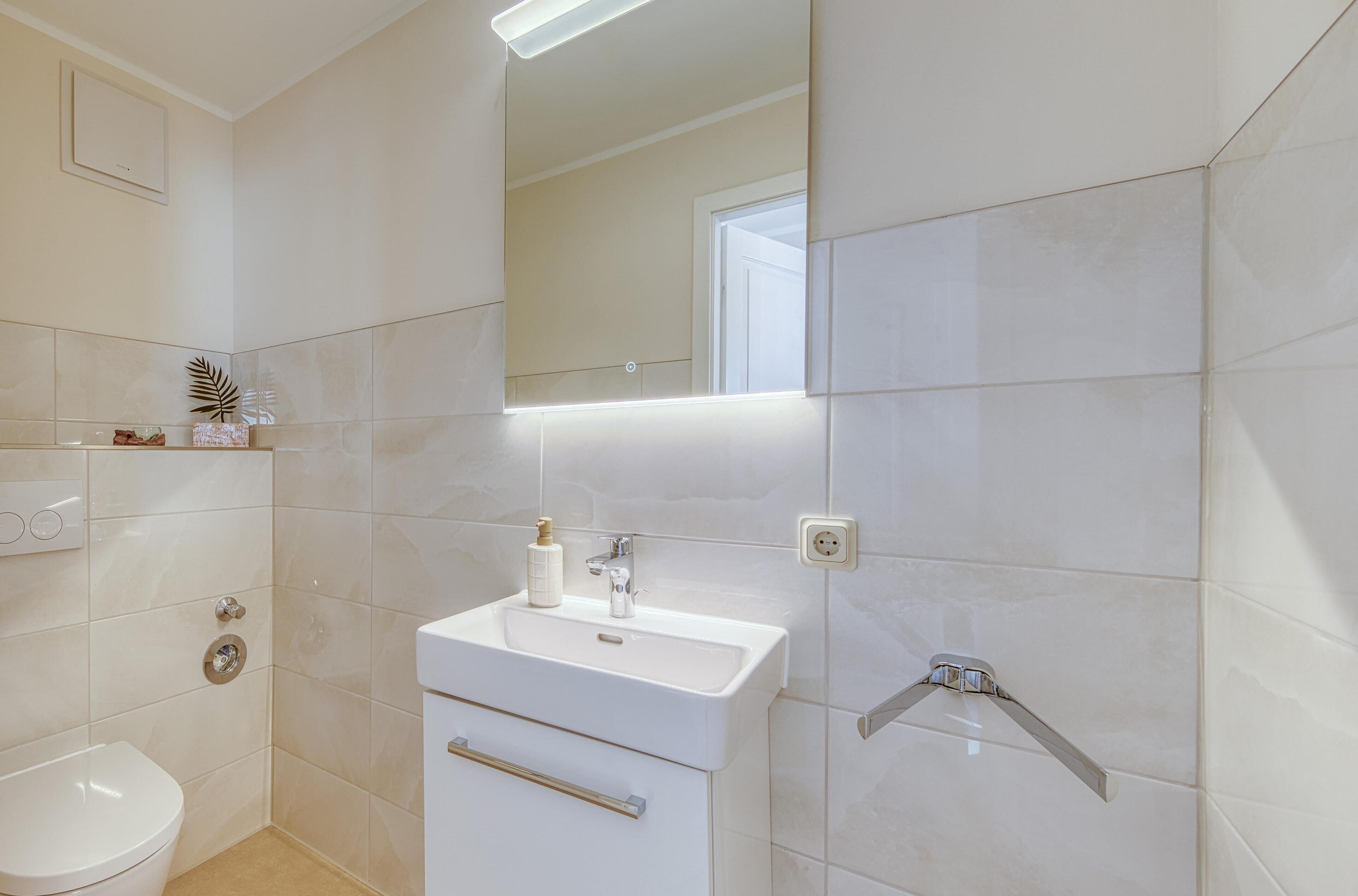 Ein modernes Badezimmer mit Waschbecken, Toilette und Dusche in Weiß.