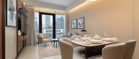 A modern hotel room with a dining area, large windows, and artwork on the walls.
