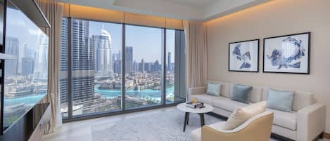 A modern living room with a large city view, a sofa, a coffee table, and artwork on the wall.