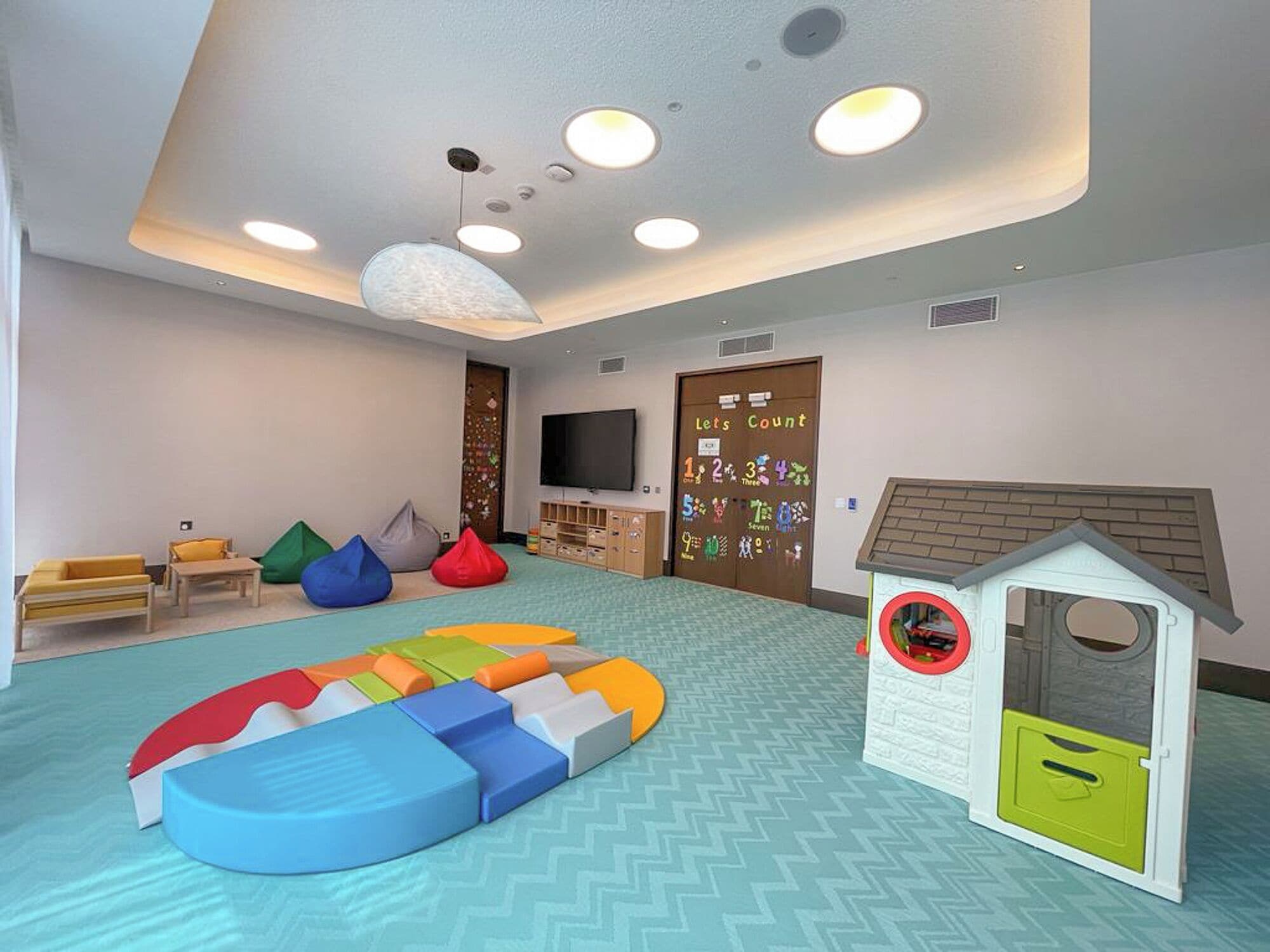 A children's play area with a slide, bean bags, and a playhouse.