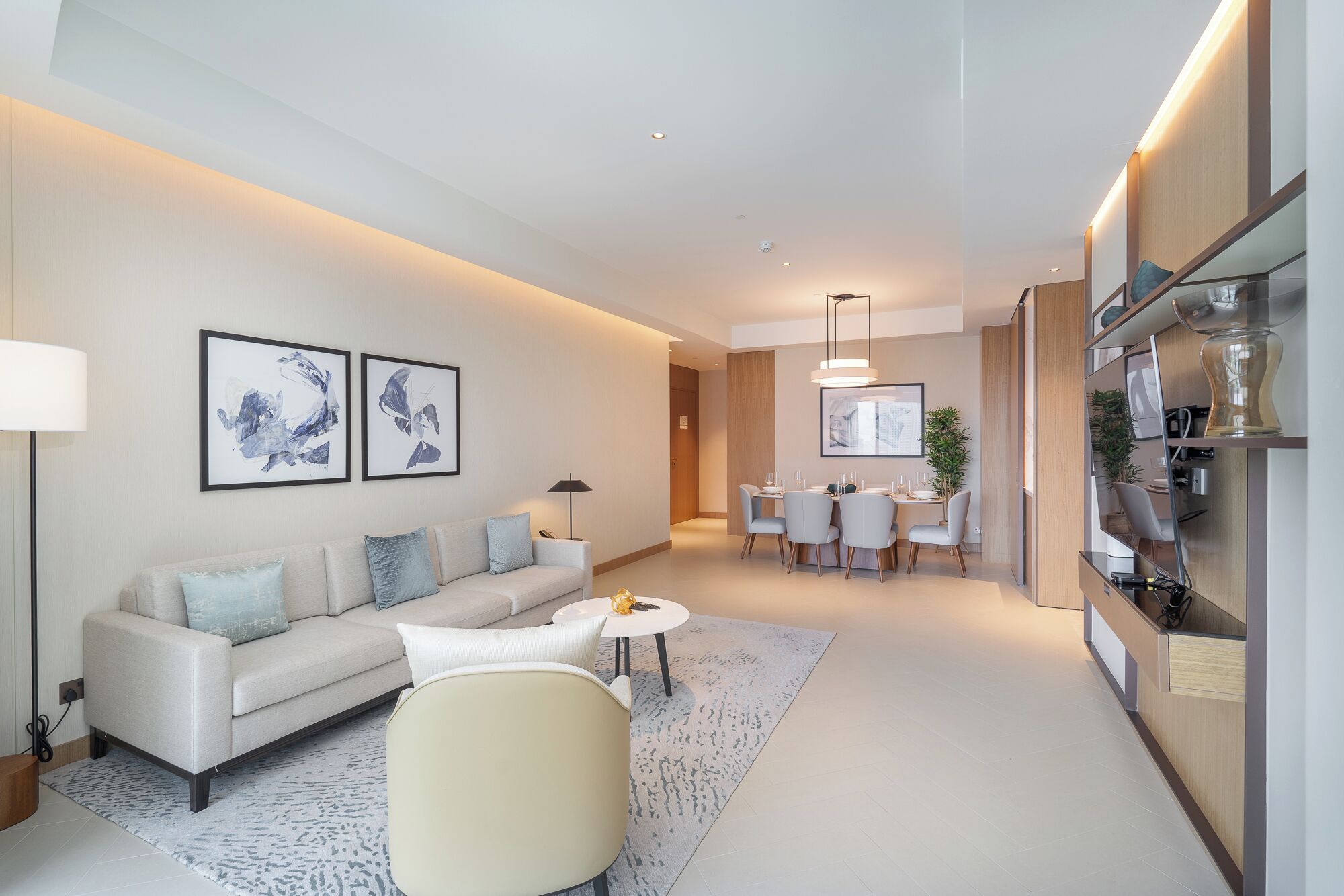 Un salon moderne comprenant un canapé, une table basse ronde et un coin repas avec une table et des chaises.