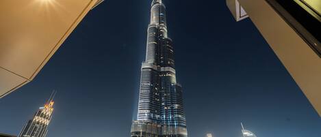 A nighttime view of the Burj Khalifa, surrounded by other illuminated skyscrapers.