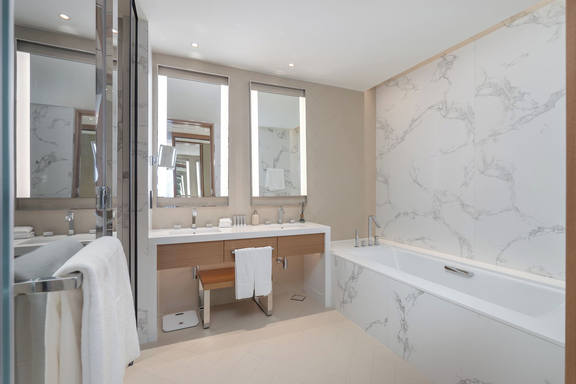 Un baño moderno con dos lavamanos, una bañera y paredes con diseño de mármol.