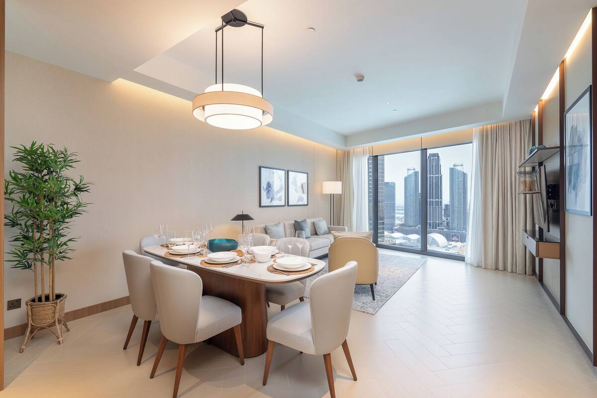 Un espace repas moderne avec une table ronde, des chaises blanches et un luminaire suspendu.