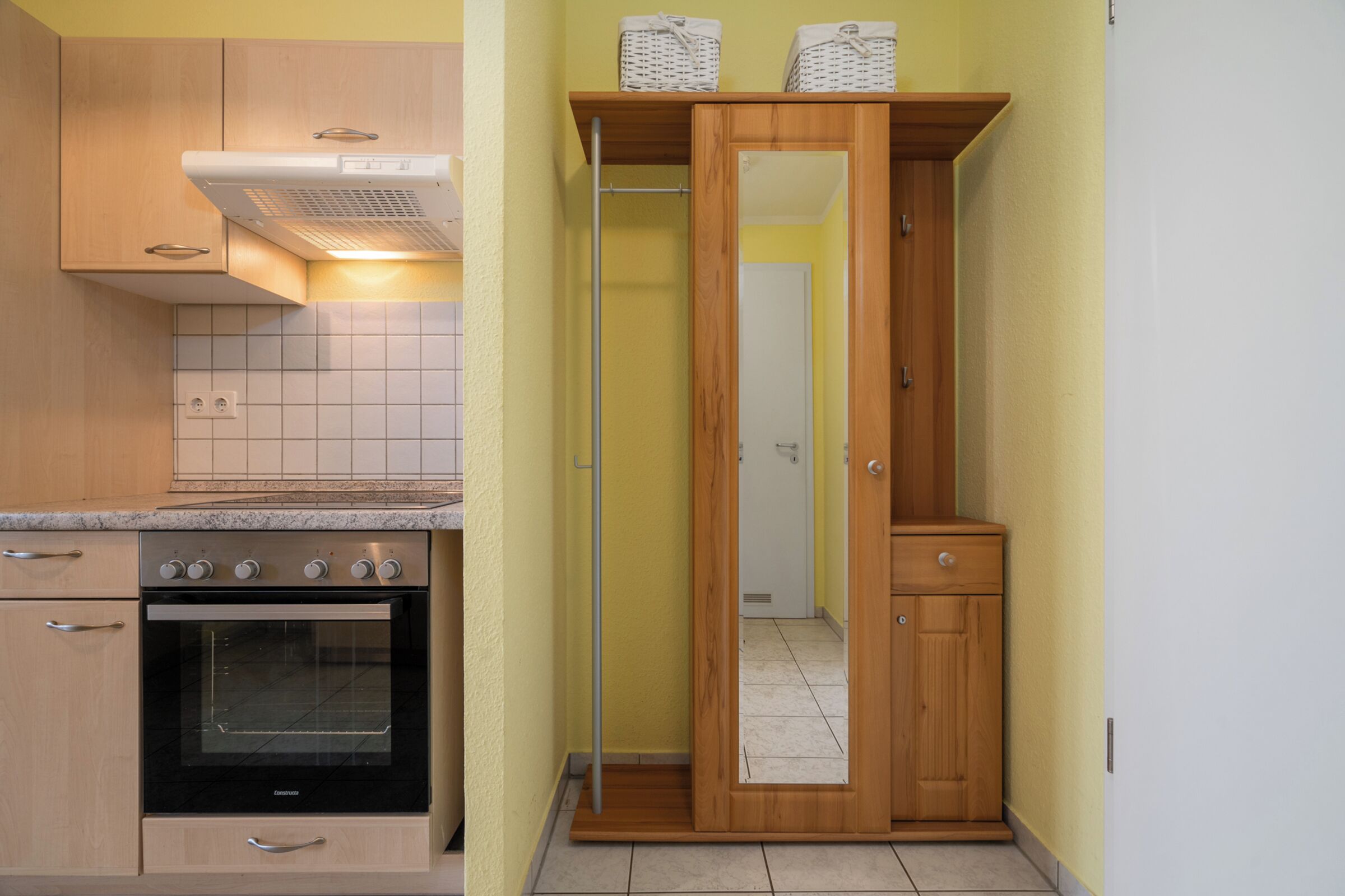 Une cuisine compacte dotée d’un four encastré, de meubles en bois et d’un petit plan de travail.