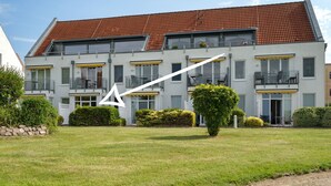 A multi-story building with a red-tiled roof, balconies, and a well-maintained lawn. - Vacation apartment "Abendsonne" with a view of the Müritz (Waren (Müritz))