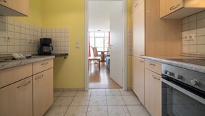 A kitchen with wooden cabinets, a coffee maker, and a view into a dining area. - Vacation apartment "Abendsonne" with a view of the Müritz (Waren (Müritz))