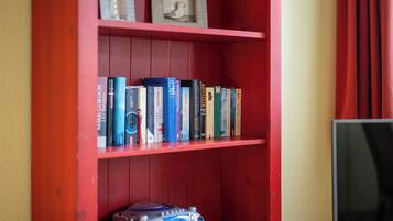 Una estantería roja con varios libros y una pequeña figurita.