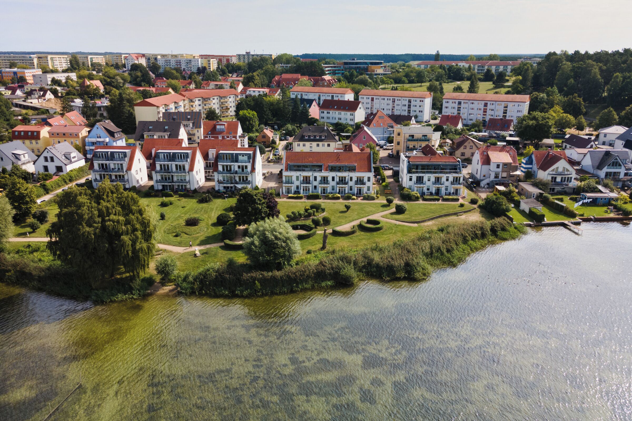 Eine Vogelperspektive auf ein Wohngebiet mit Häusern und einem See.