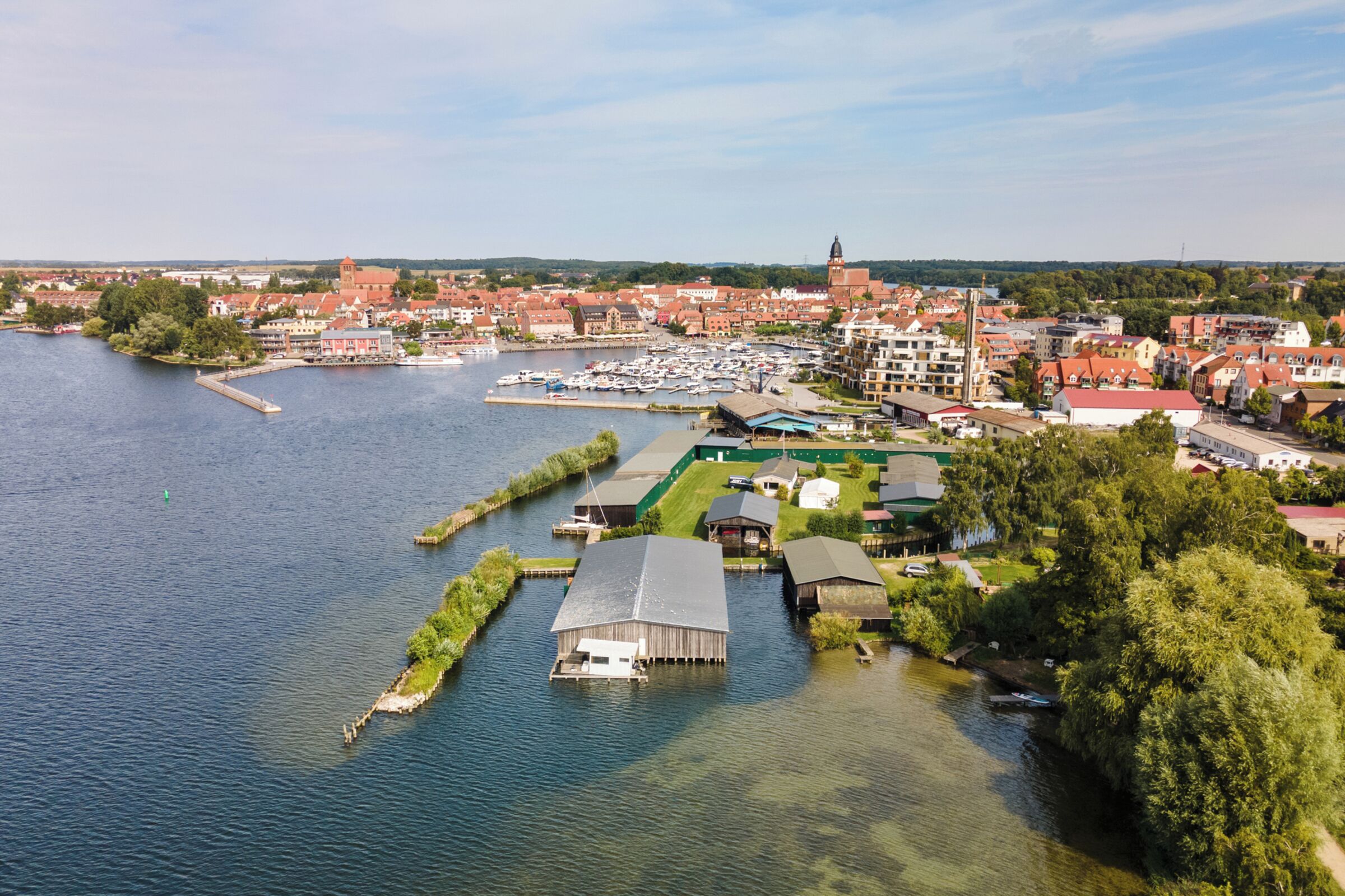 Une ville riveraine dotée d’un port de plaisance, de bâtiments et d’une église.