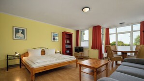 A room with a wooden bed, a wooden table, a sofa, a bookshelf, and a television. - Vacation apartment "Abendsonne" with a view of the Müritz (Waren (Müritz))