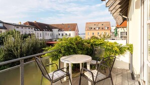 Ein Balkon mit Tisch und Stühlen, mit Blick auf ein Wohngebiet mit Häusern und Grünflächen.