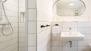 A modern bathroom with a shower, a sink, and a mirror.