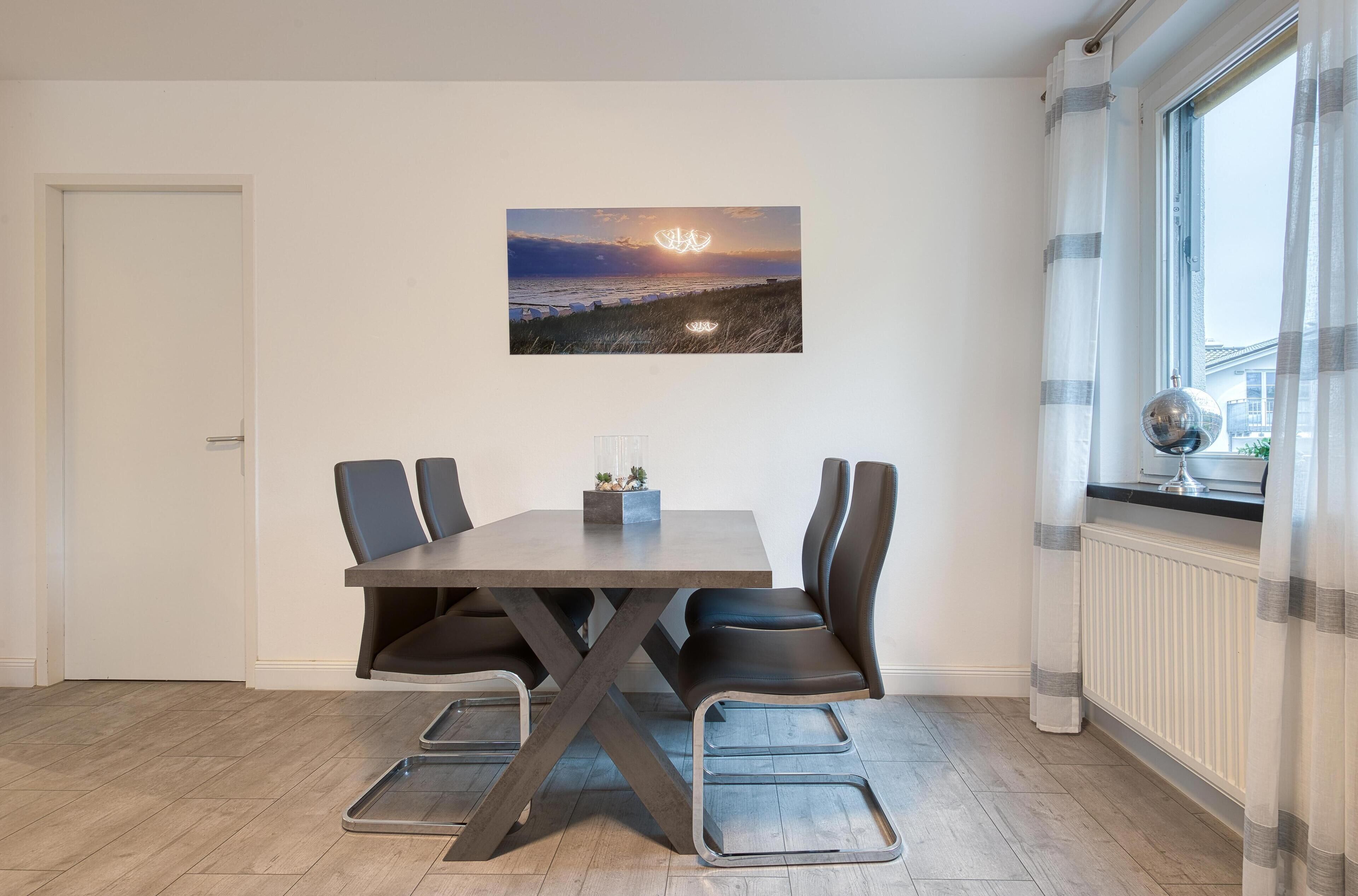 Een eethoek met een tafel, stoelen en uitzicht op de zonsondergang door een raam.