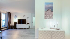 A modern bedroom with a bed, bedside table, and a large window. - 5-Star "Ostseeperle" Vacation Apartment in Zingst, Next to the Pier (Zingst)