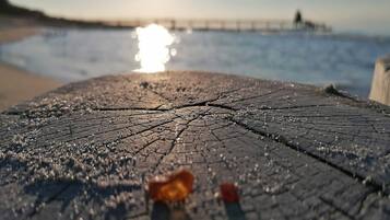 A close-up of a cracked wooden surface with water droplets, likely a dock or pier, with a blurred background of water and a distant structure.
