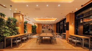 A spacious conference room with a long table and multiple chairs, surrounded by potted plants and modern lighting fixtures.