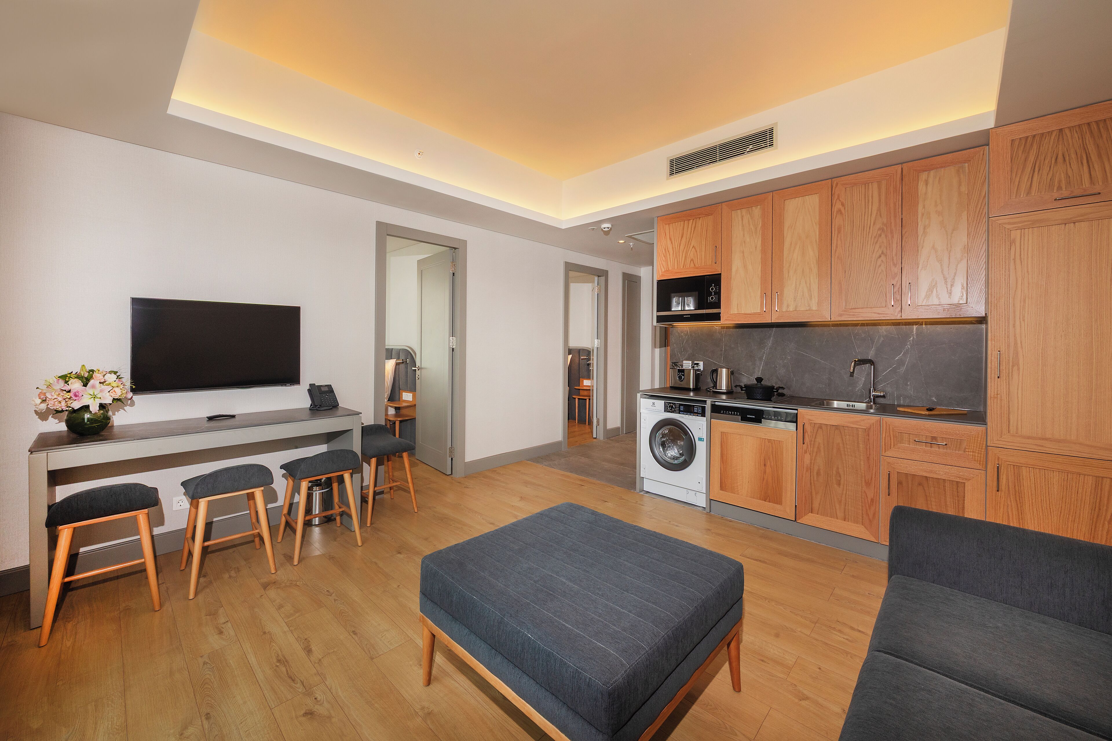 A modern kitchen with wooden cabinets, a built-in oven, and a washing machine.