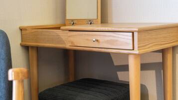 A wooden desk with a mirror, a drawer, and a cushioned stool.