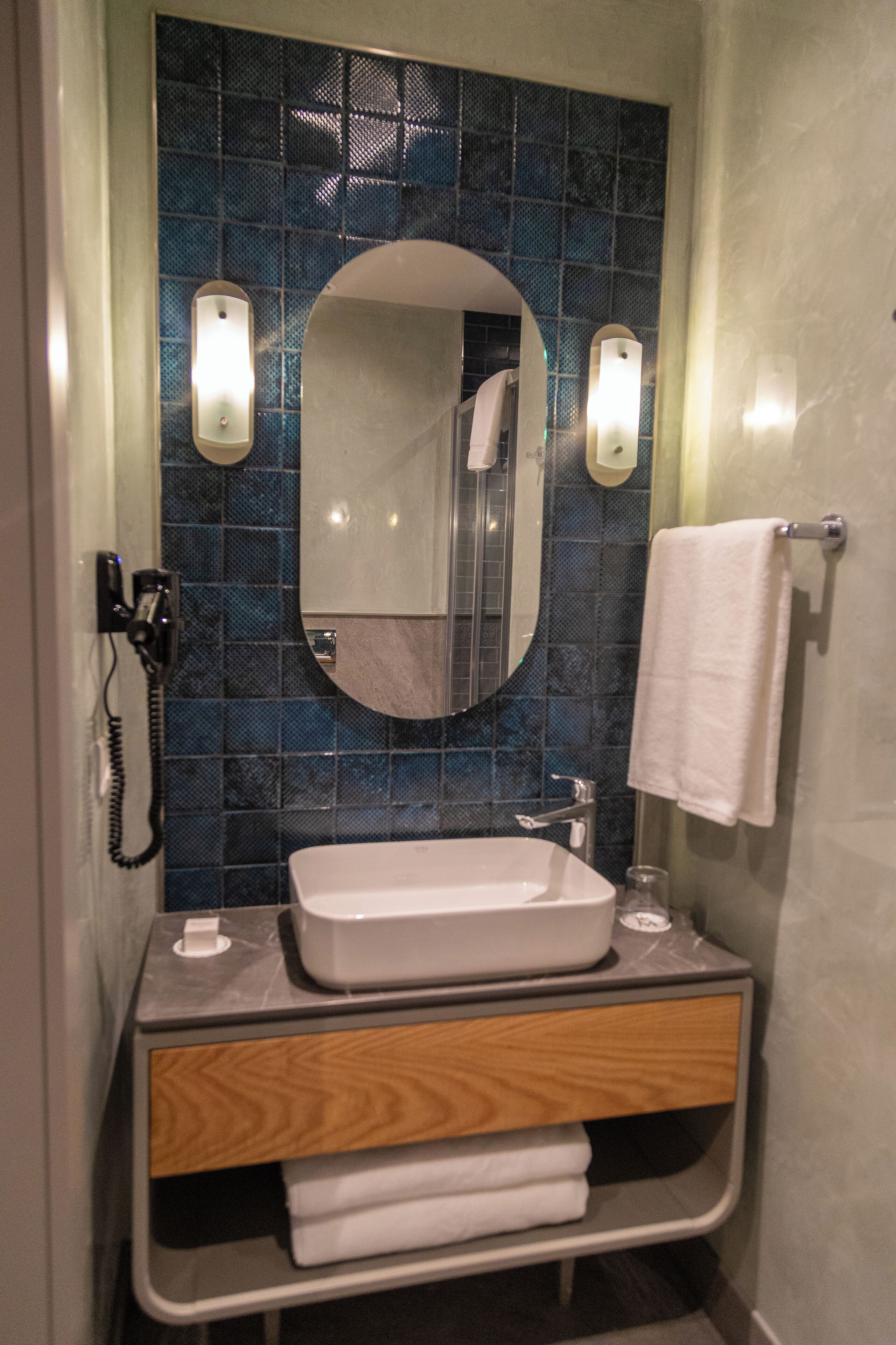 A bathroom with a white sink, a mirror, and a towel rack.