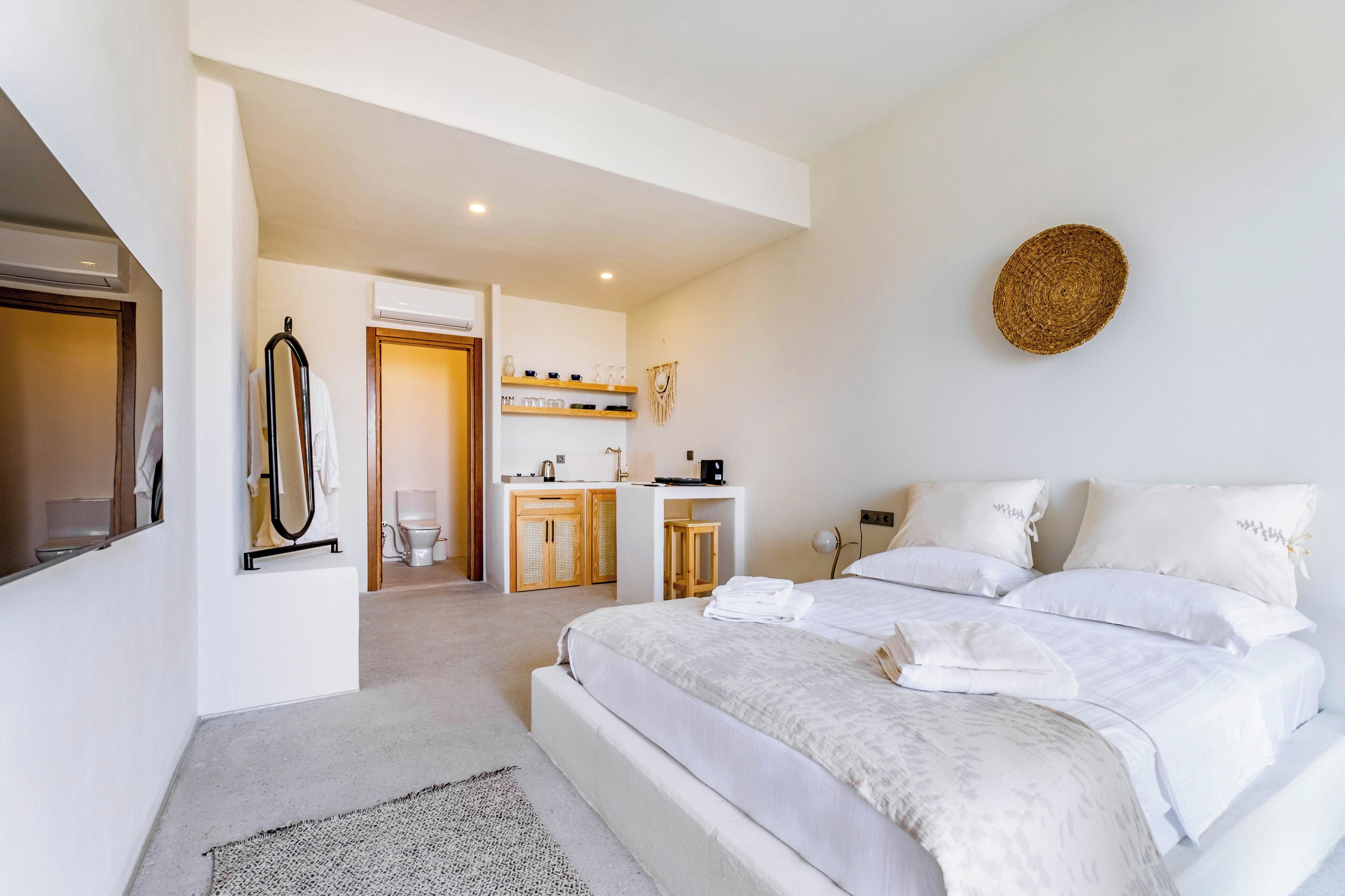 Una habitación de hotel moderna con una cama grande, un escritorio pequeño y un baño visible a través de una puerta abierta.
