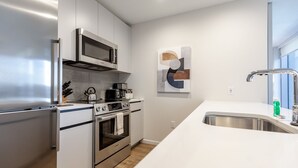 A modern kitchen with stainless steel appliances, a white countertop, and a minimalist wall art piece. - Luxury & Bright Apt Downtown Seaport (Boston MA)