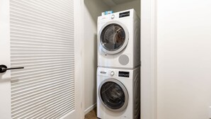 A laundry room with two stacked front-loading washing machines. - Luxury & Bright Apt Downtown Seaport (Boston MA)