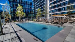 A rooftop pool with lounge chairs and a view of a modern building.