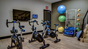 A gym with stationary bikes, a treadmill, and exercise balls.