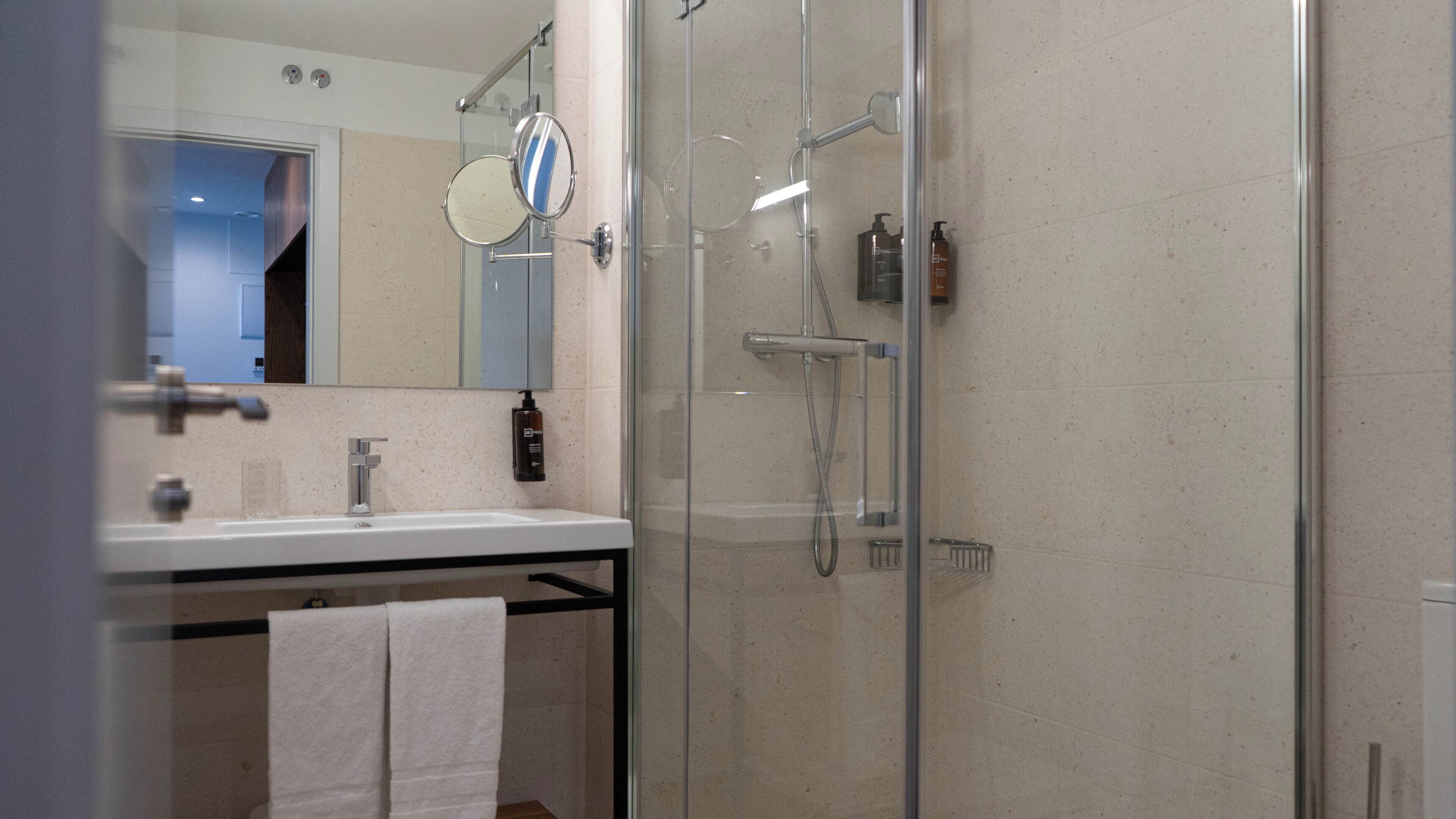 Une salle de bain moderne avec une douche à parois de verre, un lavabo avec un miroir et un porte-serviettes.
