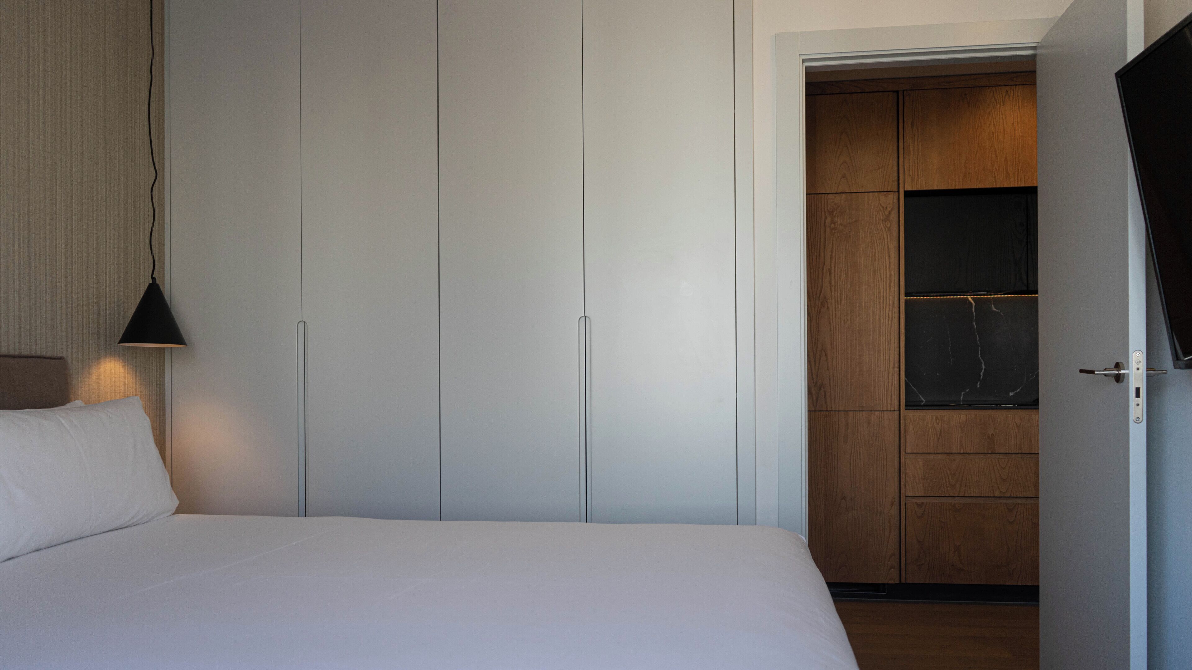 Un dormitorio con cama, lámpara colgante y armario con espejo.