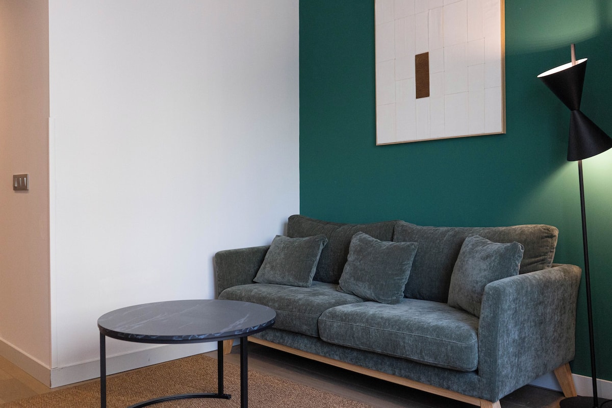 A modern living room with a grey sofa, a small round table, and a floor lamp.