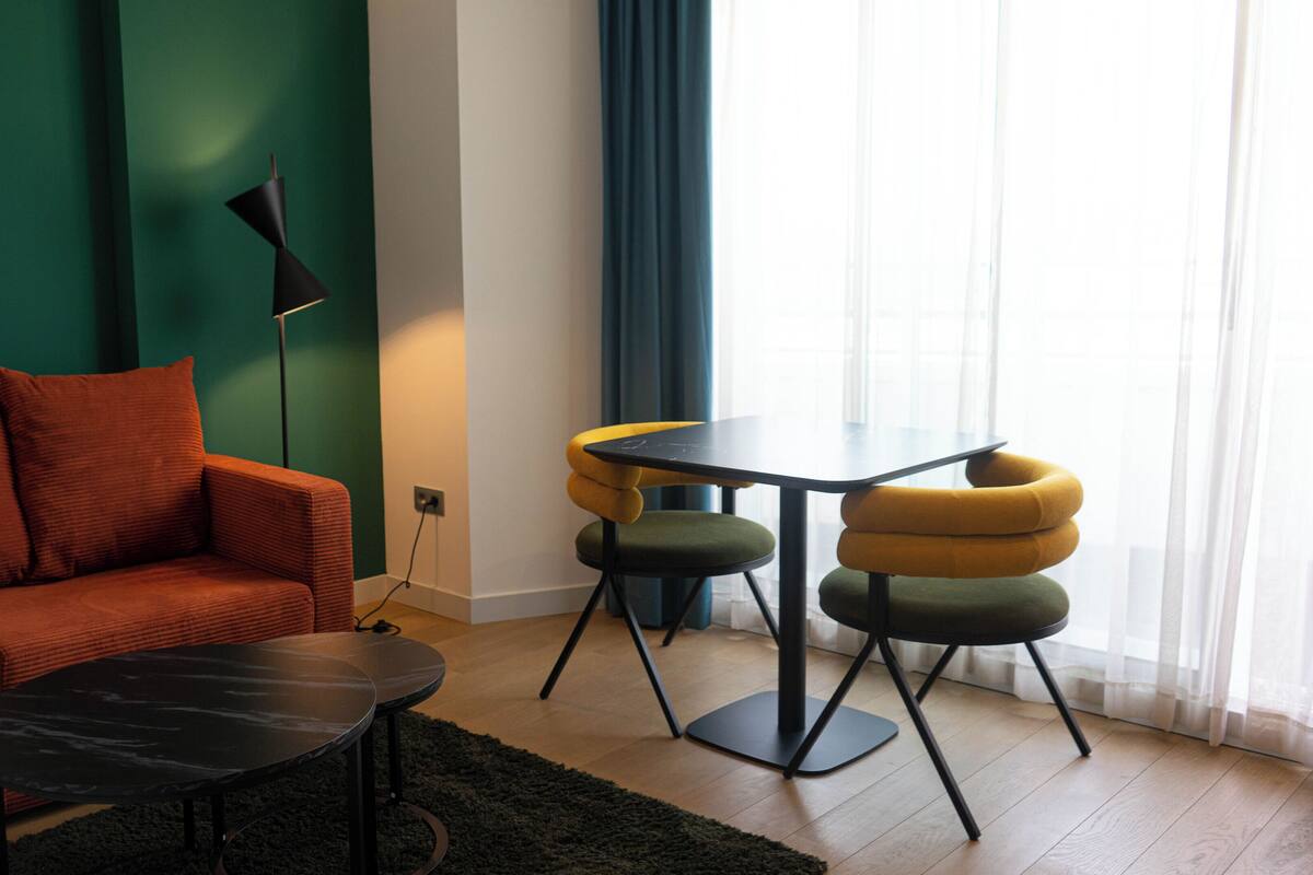 A modern living room with a red sofa, a black coffee table, and a unique yellow and green chair set.