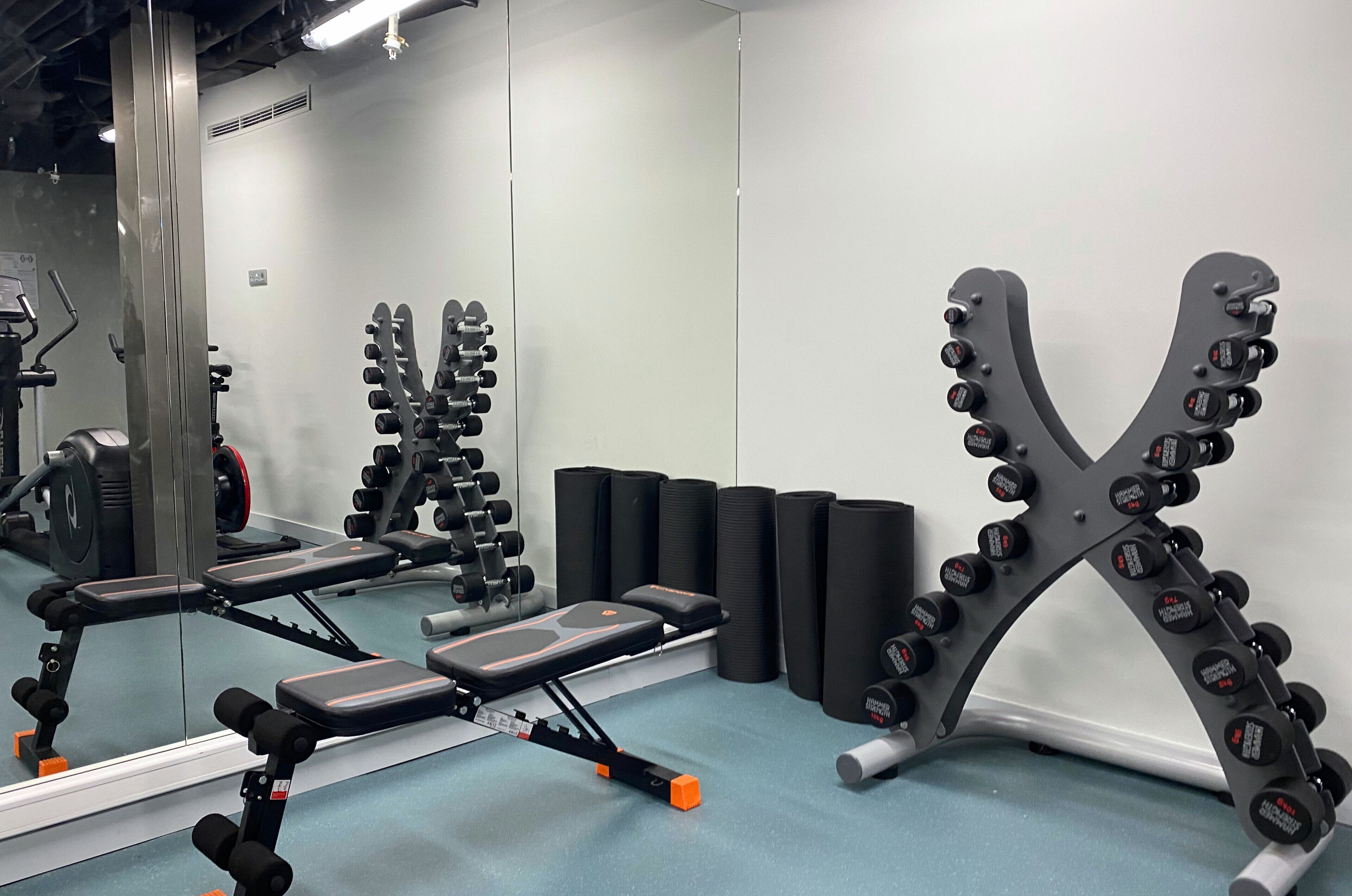 Ett gym med utrustning för styrketräning, träningsbänkar och träningsbollar.