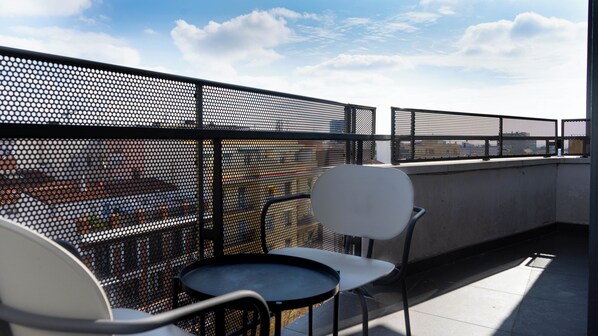 A rooftop terrace with a metal fence, two chairs, and a small round table. - Be Mate Trafalgar (Madrid)