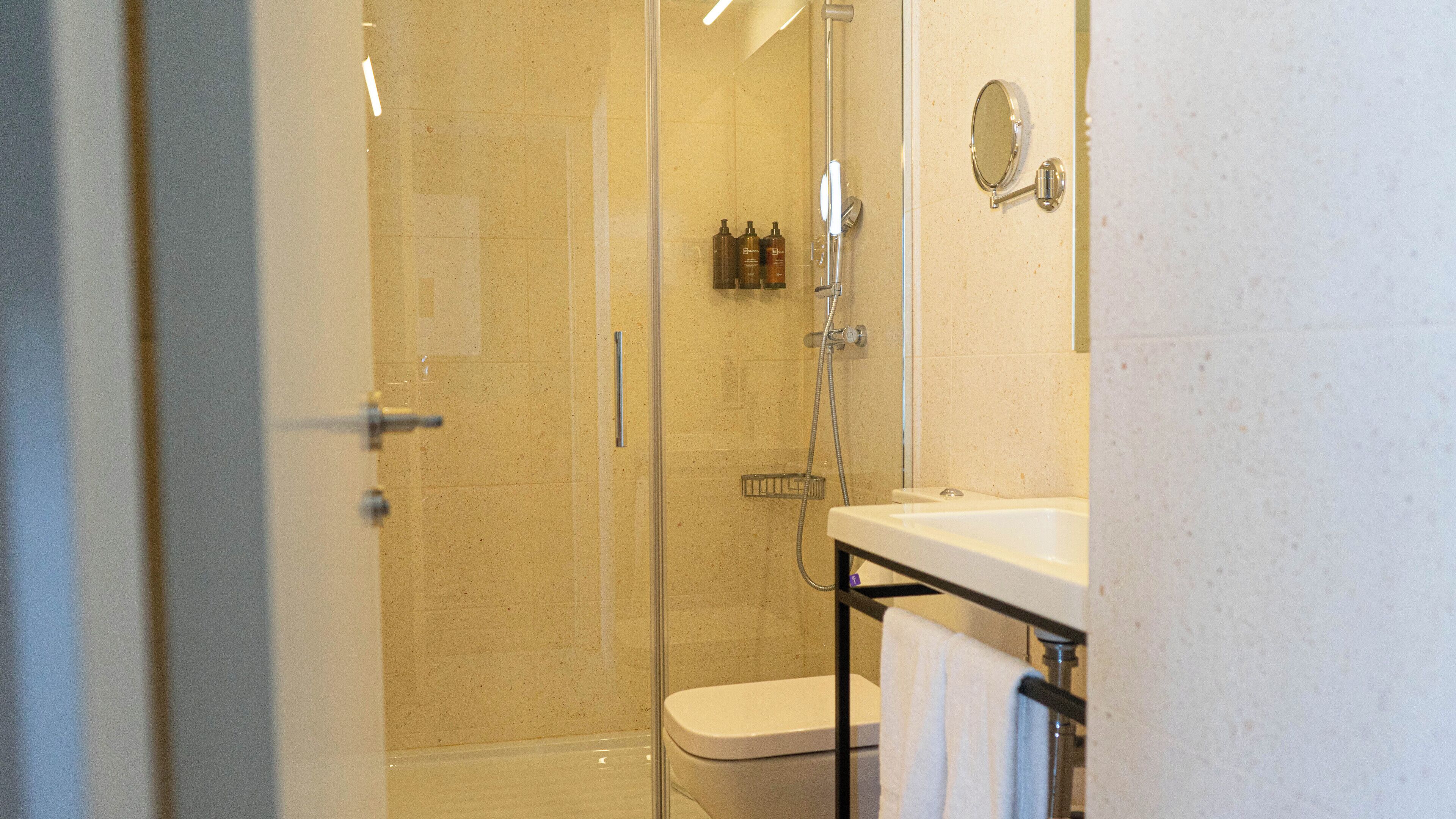 Une salle de bain avec une douche à parois de verre, des toilettes et un lavabo, avec une serviette suspendue sur le côté.