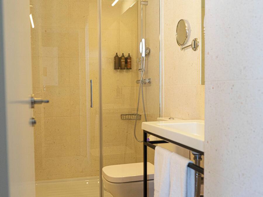 Un baño con ducha de vidrio, inodoro y lavamanos con una toalla colgando al lado.