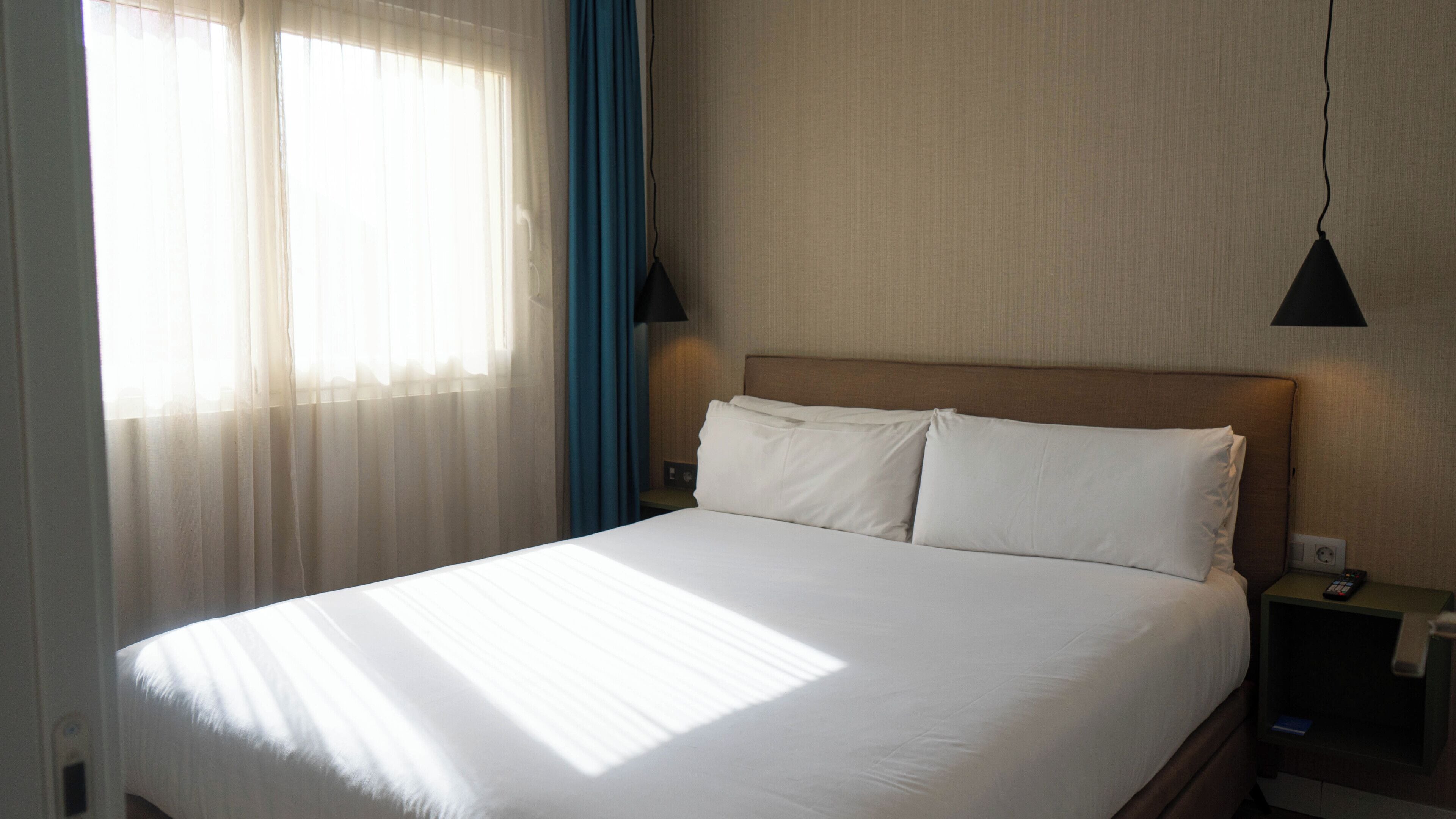 Una cama bien hecha con sábanas blancas en una habitación de hotel.