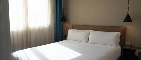 Una cama bien hecha con sábanas blancas en una habitación de hotel.