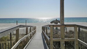 Pasarela de madera que conduce a una playa con una estructura de paja.