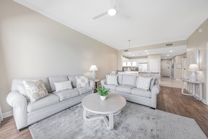 A living room with a grey sectional sofa, a round coffee table, and a ceiling fan.