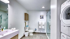 A modern bathroom with a sink, toilet, and a Bosch washing machine. - Luxury Apt Kendall Sq with Amenities (Cambridge MA)