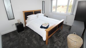 Quarto com cama, mesa de cabeceira, luminária, janela e vista para o exterior.