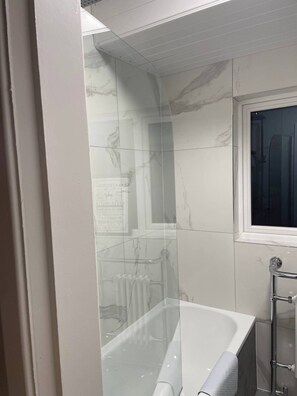 Huis | Badkamer | Een bad/douchecombinatie, een diep bad, een haardroger, handdoeken