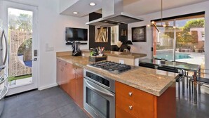A modern kitchen with a large island, stainless steel appliances, and a view of the outdoor pool.