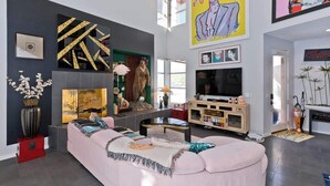 A modern living room with a large sofa, a flat-screen TV, and artwork on the walls.