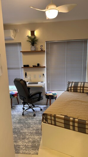 A bedroom with a bed, a desk, a chair, a ceiling fan, and a window with blinds. - Beautiful and complete loft in Fazenda (Fazenda Itajaí)