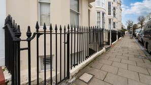 A row of beige apartment buildings with black iron fences, a paved sidewalk, and parked cars. - Host Stay Waterloo Apartment (Hove)