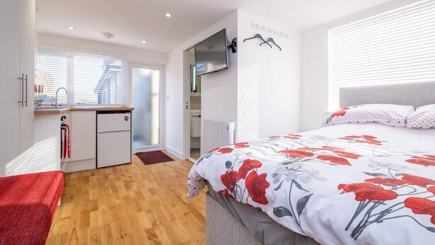 Une chambre moderne avec un lit, une petite kitchenette et une vue sur la ville.