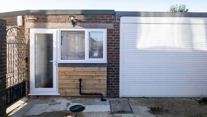 Un garage avec une porte en bois, une fenêtre avec des stores et un portail en métal.